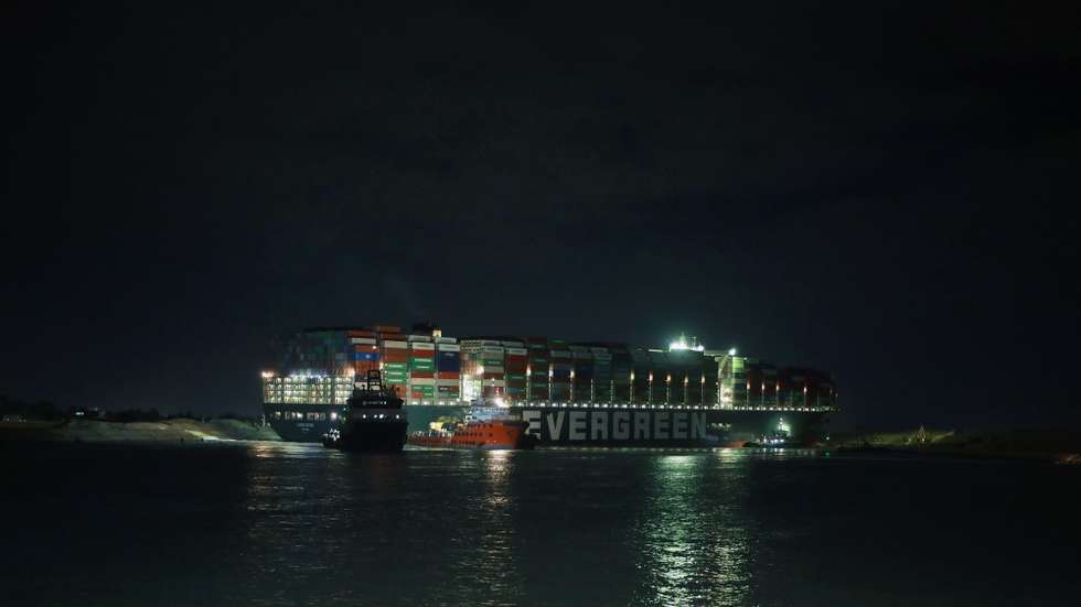 epa09101925 The Ever Given container ship which ran aground in the Suez Canal, Egypt, 27 March 2021. The Ever Given, a large container ship ran aground in the Suez Canal on 23 March, blocking passage of other ships and causing a traffic jam for cargo vessels. The head of the Suez Canal Authority announced that 'the navigation through the Suez Canal is temporarily suspended' until the floatation of the Ever Given is completed. Its floatation is being carried out by eight large tugboats that are towing and pushing the grounding vessel  EPA/KHALED ELFIQI