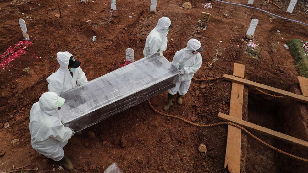 epa08653729 Workers clad in hazmat suits carry the coffin of a coronavirus victim during a funeral at Pondok Ranggon cemetery in Jakarta, Indonesia, 08 September 2020. According to media reports, Jakarta’s Pondok Ranggon Covid-19 dedicated cemetery is expected to run out of space for victim's graves in October. The city administration has burried more than 5,000 bodies under Covid-19 protocols since the pandemic began.  EPA/MAST IRHAM
