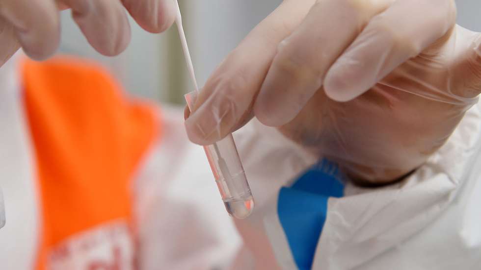epa08900904 A health workers performs a rapid coronavirus disease (COVID-19) antigen test on a swab sample, for health workers and guests of the Cottolengo hospital, organized by the association 'Camminare insieme' (walking together), in Turin, northern Italy, 23 December 2020.  EPA/ALESSANDRO DI MARCO
