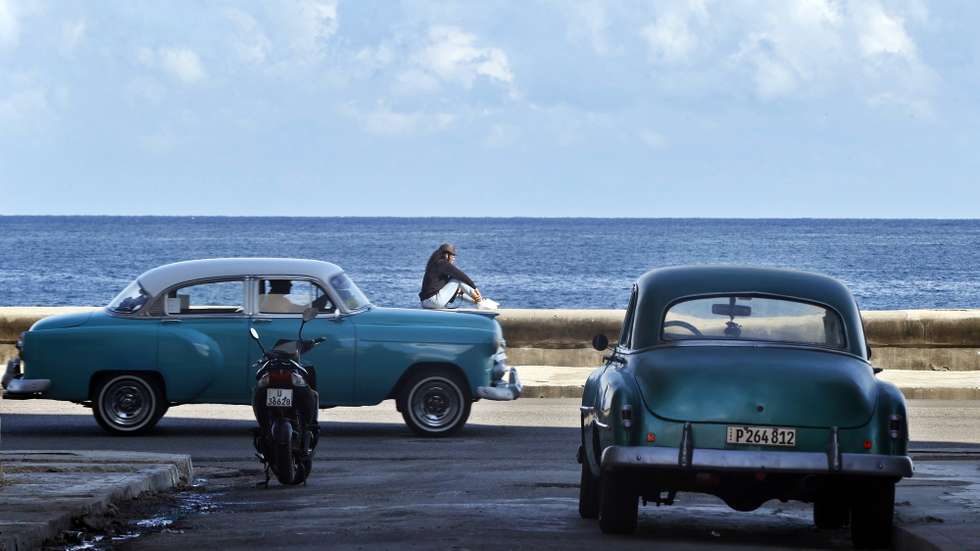 epa12849151 A person rests at the seafront promenade as a classic car drives by in Havana, Cuba, 25 March 2026. The Caribbean nation has been experiencing a severe crisis since mid-2014, which has deepened with the oil embargo imposed by the US government since January 2026. The United Nations (UN) has described the US measures as 'actions that violate human rights.'  EPA/ERNESTO MASTRASCUSA