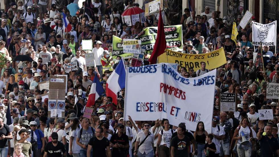 epa09434189 Protesters with a poster reading 'Firefighters and health workers together, united' during a demonstration against the COVID-19 sanitary pass, which grants vaccinated individuals greater ease of access to venues, in Montpellier, France, 28 August 2021. For the seventh consecutive week, thousands of French demonstrators have taken to the streets in several cities across the country to protest against measures to curb the spread of coronavirus.  EPA/GUILLAUME HORCAJUELO