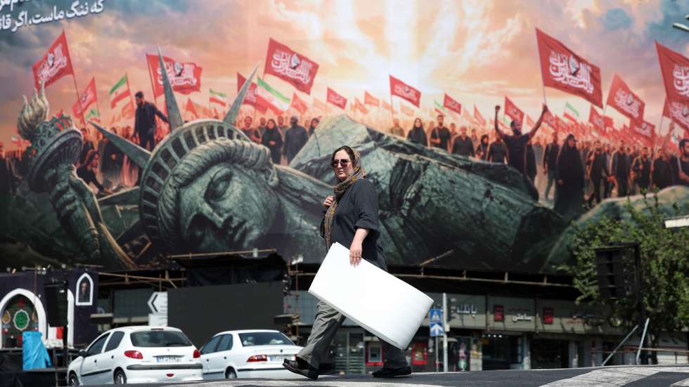 epa13165940 An Iranian woman walks next to an anti-US billboard at the Enghelab square in central Tehran, Iran, 13 August 2026. Tensions between Iran and the US remain high as opposing claims persist over shipping control in the Strait of Hormuz.  EPA/ABEDIN TAHERKENAREH RESTRICTIONS: NO Access Israel Media/Persian Language TV Stations Outside Iran/Strictly No Access BBC Persian/VOA Persian/Manoto TV/Iran International TV. (As mandated by Iran's Directorate General for Foreign Media) --