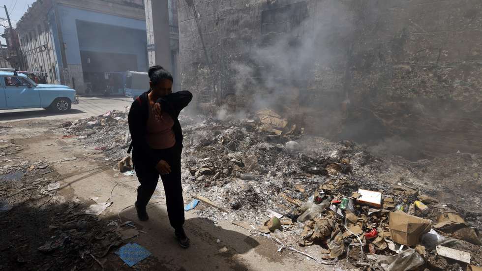 epa13003354 A person shields themselves from smoke rising from a trash fire in Havana, Cuba, 29 May 2026.  EPA/ERNESTO MASTRASCUSA