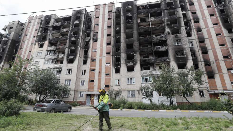 epa10112752 A communal worker mows the grass in front of a damaged residential building in the city of Irpin, near Kyiv, Ukraine, 09 August 2022 as life goes on amid Russia's military invasion of the country. Irpin as well as other towns and villages in the northern part of the Kyiv region became battlefields and were heavily shelled when Russian troops tried to reach the Ukrainian capital Kyiv in February and March 2022. Russian troops on 24 February entered Ukrainian territory, starting a conflict that has provoked destruction and a humanitarian crisis.  EPA/SERGEY DOLZHENKO