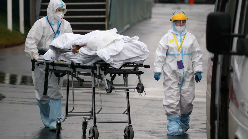 epa09523547 Health workers escort a Covid-19 patient to the hospital complex in the Kommunarka settlement in Moscow, Russia, 14 October 2021. Russia is facing a new wave of Covid-19 infections, with additional 986 coronavirus-related deaths reported on 14 October bringing the official coronavirus death toll to 220,315.  EPA/MAXIM SHIPENKOV