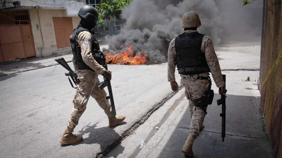 epa10800644 Policemen walk by a tire fire during a demonstration in Port-au-Prince, Haiti, 14 August 2023. Haitian National Police officers dispersed the demonstrators with tear gas after residents of the Carrefour-Feuilles area protested against the insecurity they suffer due to the action of armed gangs.  EPA/Johnson Sabin