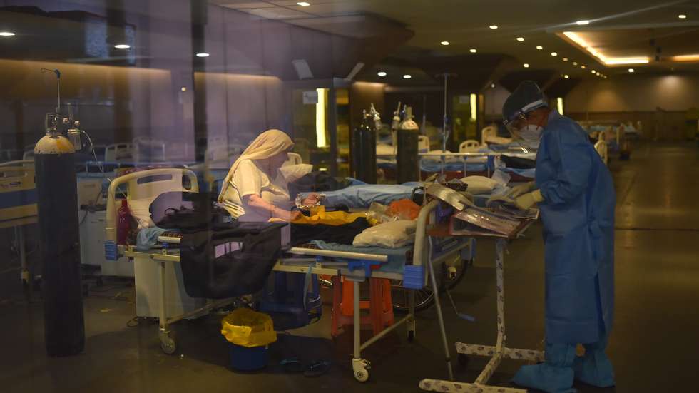 epa09225150 Indian doctor wearing Personal Protective Equipment (PPE) examines patients inside a COVID-19 care center and isolation ward facility near a Hospital in New Delhi, India, 24 May 2021. India on 24 May surpassed the barrier of 300,000 deaths from coronavirus, registering more than 4,000 deaths a day, while infections maintain a downward trend, with just over 220,000 cases in the last 24 hours.  EPA/IDREES MOHAMMED