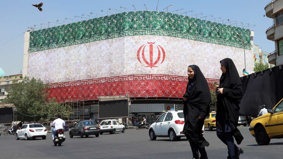 epa13035937 Veiled Iranian women walk past a billboard featuring Iran's national flag at Enqelab Square in Tehran, Iran, 14 June 2026. US President Donald Trump saying on a social media platform that a deal could be signed soon.  EPA/ABEDIN TAHERKENAREH RESTRICTIONS: NO Access Israel Media/Persian Language TV Stations Outside Iran/Strictly No Access BBC Persian/VOA Persian/Manoto TV/Iran International TV. (As mandated by Iran's Directorate General for Foreign Media) --