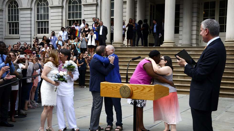 epa04820605 New York City Bill de Blasio (R) looks on as three couples (L-R) Katrina Council and Sara Joseph, Tom Kirdahy and playwright Terrence McNally, Cindy Jackson and Denice Niewinski, celebrate after being married during a ceremony outside of New York City Hall in New York, New York, USA 26 June 2015. The event, during which two couples were officially married along with the reaffirming of vows, celebrated today's ruling by the United States Supreme Court which legalized gay marriages nationwide.  EPA/JUSTIN LANE