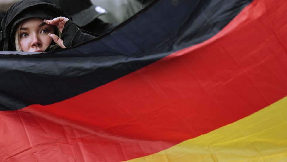 epa11776647 A demonstrator behind a German flag during a right-wing demonstration under the slogan 'For law and order: against left-wing extremism and politically motivated violence', in Berlin, Germany, 14 December 2024.  EPA/HANNIBAL HANSCHKE