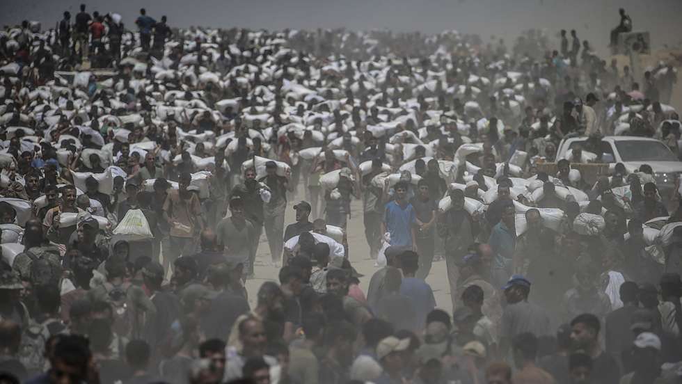 epa12266151 Internally displaced Palestinians carry bags of flour near a food distribution point in Zikim, northern Gaza Strip, 27 July 2025. The Israeli army declared a 'tactical pause' in military operations in parts of the Gaza Strip on 27 July, to facilitate the safe passage of humanitarian aid convoys. More than 130 Palestinians, the majority of whom children, have died of malnutrition in the Gaza Strip, the Palestinian Ministry of Health said on 27 July.  EPA/MOHAMMED SABER