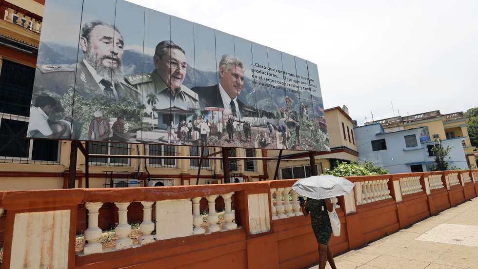 epa13011424 A woman walks past a billboard displaying images of Cuban President Miguel Diaz-Canel (R), General and former President Raul Castro (C), and the late former Cuban President Fidel Castro (L) on 01 June 2026, in Havana, Cuba (issued 02 June 2026). Former Cuban President Raul Castro will turn 95 on 03 June 2026, retired from all formal positions but simultaneously in the spotlight, leading bilateral dialogue with Washington and having been criminally indicted a few days ago in the US.  EPA/Ernesto Mastrascusa
