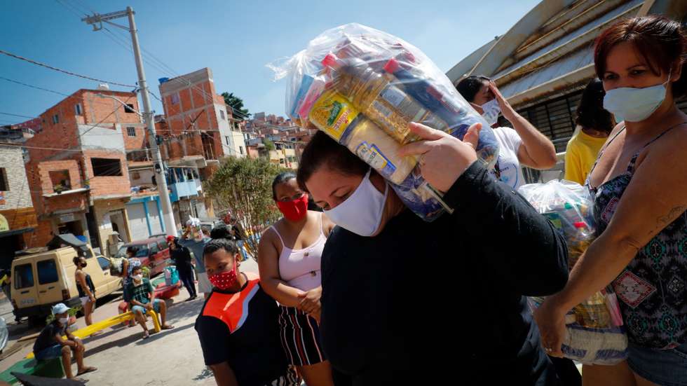 epa09100579 Residents receive food donations on 23 March 2021, in the Paraisopolis favela, on Paulista Avenue, in Sao Paulo, Brazil (Issued 27 March 2021). One year after the start of the pandemic, deaths and cases of covid-19 increase day by day in Brazil, but aid for the poorest does not stop falling. In Paraisopolis, one of the largest favelas in Sao Paulo, hunger hits the door of thousands of families hard.  EPA/Fernando Bizerra