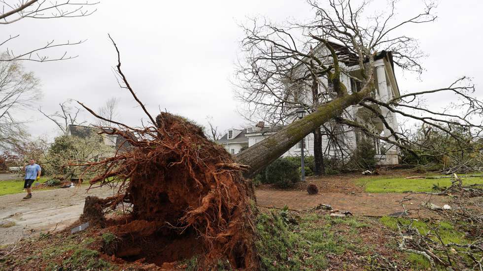 epa09099466 A large uprooted tree resting on a house after an apparent tornado swept through Newnan, Georgia USA, 26 March 2021. The spring severe weather outbreak left at least six people dead in Alabama and Georgia.  EPA/ERIK S. LESSER