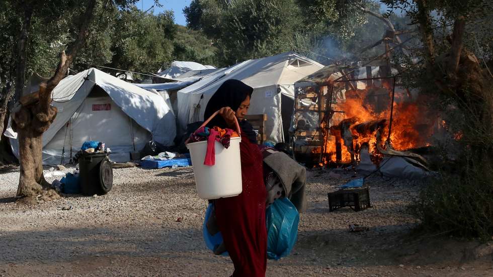 epa08763990 YEARENDER 2020 DISASTERS AND ACCIDENTSAn Asylum seeker carries possessions away from a fire in the Moria refugees camp on the island of Lesvos, Greece, 10 September 2020. A second fire broke out in the Moria refugee camp on 10 September. A passenger ferry and two Navy landing ships will accommodate about 2,000 refugees who are homeless after the fire at Moria, Migration and Asylum Minister Notis Mitarachi said. The island of Lesvos was declared in state of emergency for four months, by order of Deputy Civil Protection and Management Crises Minister Nikos Hardalias and the general secretary of civil protection Vassilis Papageorgiou. EPA/ORESTIS PANAGIOTOU