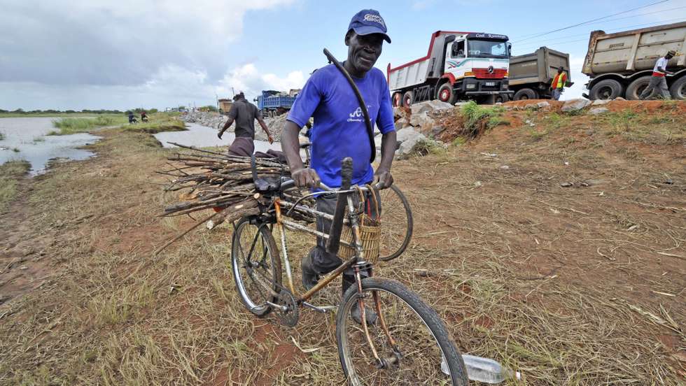 Um homem desloca-se com a sua bicicleta por um atalho devido às estradas estarem submersas pela água das cheia na sequência da tempestade "Dando", que assola o sul de Moçambique, junto às tendas do centro de acomodação na zona 3 de Fevereiro, na província de Maputo, em Moçambique, 26 de janeiro de 2012. A tempestade, que há quase duas semanas atinge o sul de Moçambique, forçou centenas de famílias a abandonarem o bairro Sambo, na zona de 3 de Fevereiro, a região onde a EN1 ficou temporariamente cortada, devido à subida do nível das águas do rio Incomáti, interrompendo a circulação rodoviária entre o sul e o norte do país. (ACOMPANHA TEXTO). ANTONIO SILVA / LUSA