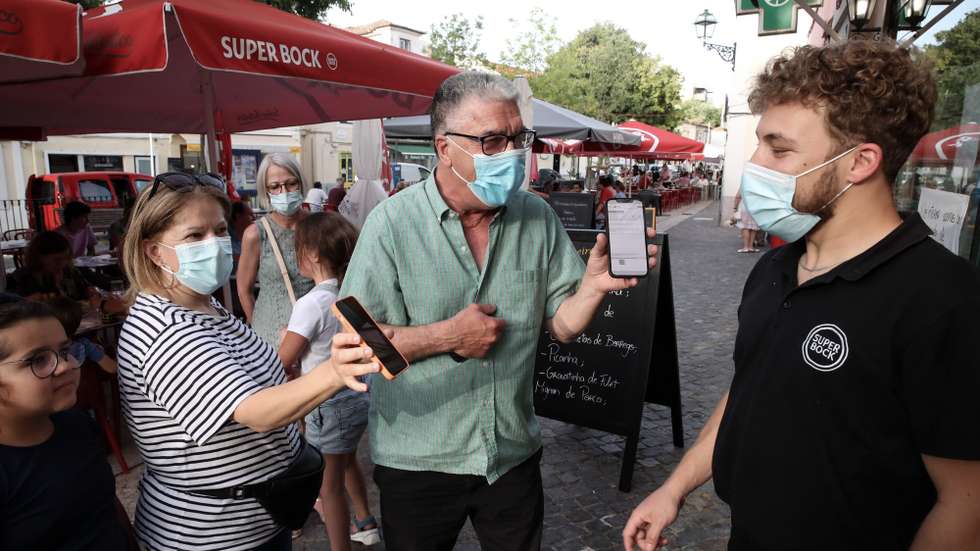 Clientes exibem o certificado digital à entrada de um restaurante em Lisboa, após o Governo decreta que os restaurantes em concelhos de risco elevado ou muito elevado – um total de 60 – passam a ter de exigir certificado digital ou teste negativo à covid-19 a partir das 19:00 de sexta-feira e aos fins de semana para refeições no interior, Lisboa, 10 de julho de 2021. As pessoas em esplanadas que precisarem de entrar nos restaurantes para acesso aos serviços comuns, como instalações sanitárias, ou para efetuarem pagamento, estão dispensadas de apresentar um teste negativo à covid-19 ou o certificado digital. MANUEL DE ALMEIDA/LUSA