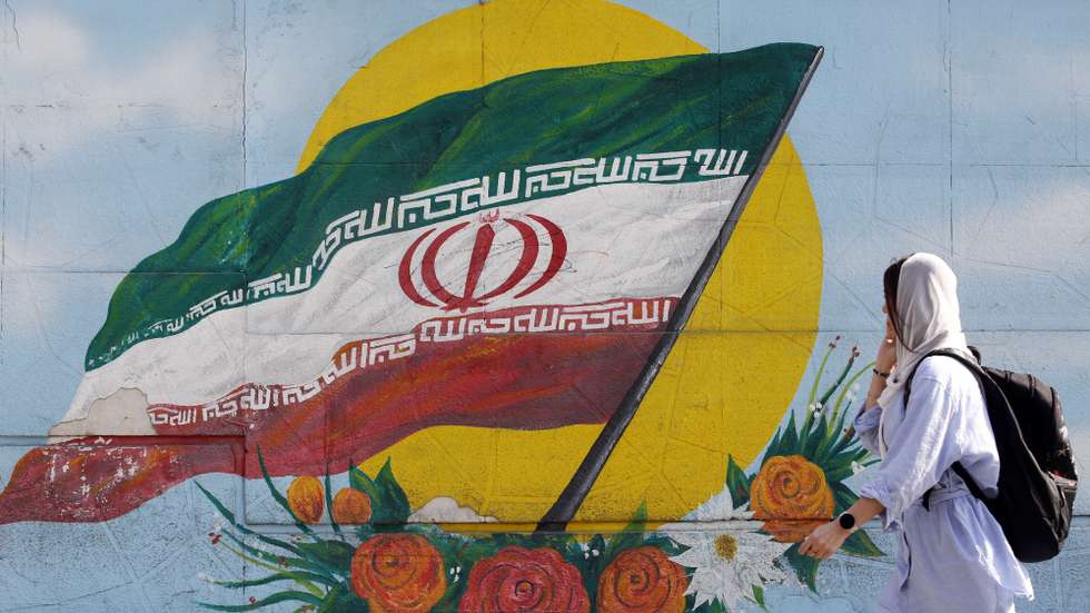 epa10295546 A woman walks past a graffiti showing the Iranian national flag in Tehran, Iran, 09 November 2022. Iran has been rocked by anti-government protests, with supporters worldwide, following the death in September 2022 of Masha Amini, a 22-year-old girl who died while in police custody after being detained for breaking Iran's strict dress code for women. Iranian leaders condemned the protests and accused the United States and Israel of planning the uprising.  EPA/ABEDIN TAHERKENAREH