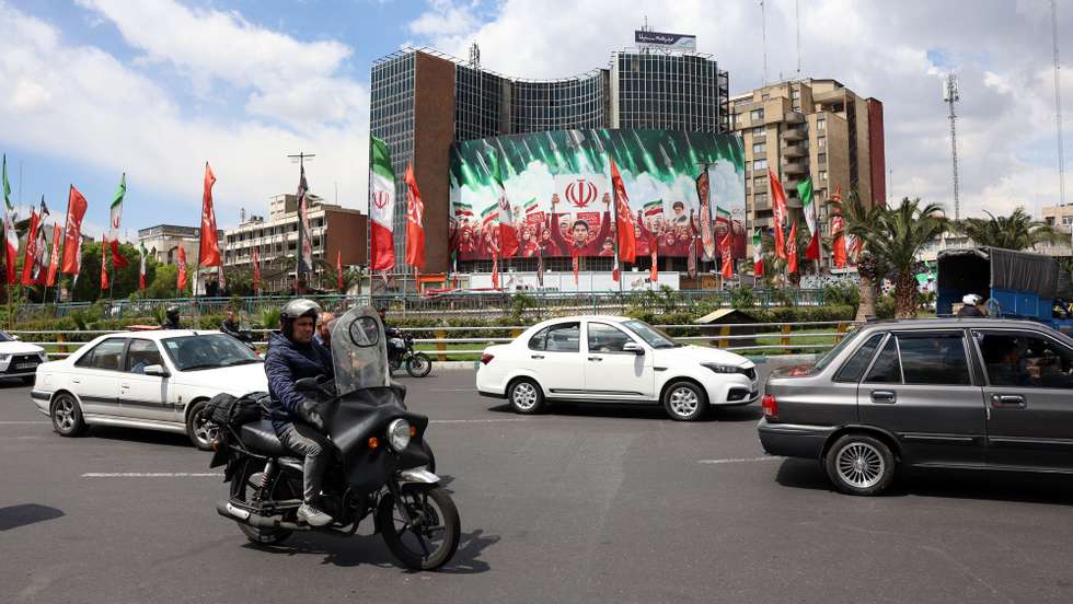 epa12871325 Iranians drive past a large political billboard displaying Iran's national flags at Valiasr Square in Tehran, Iran, 06 April 2026. The US president has given Iran a 48-hour deadline to reach a deal and reopen the Strait of Hormuz.  EPA/ABEDIN TAHERKENAREH