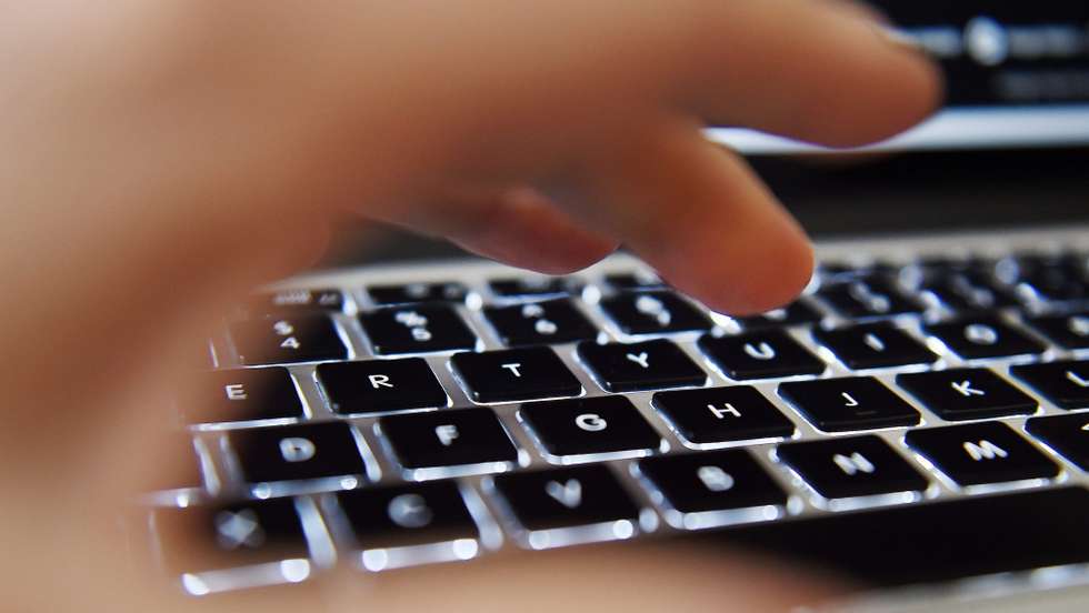 Uma mão sobre o teclado de um computador portátil