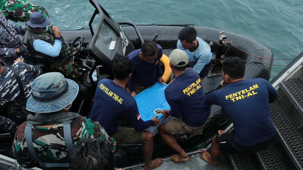 epa08932563 Indonesian Navy personnel move a plastic container carrying a black box of the crashed Sriwijaya Air plane, recovered from the wreckage, onto a sea reader boat, in waters off Jakarta, Indonesia, 12 January 2021. Indonesia's navy divers recovered the flight data recorder (FDR) of the Sriwijaya Air Boeing 737-500 plane that crashed into the waters off the coast of Jakarta with 62 people on board.  EPA/STR