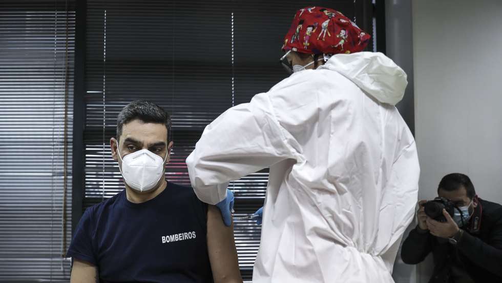 Um bombeiro é vacinado por uma profissional de saúde