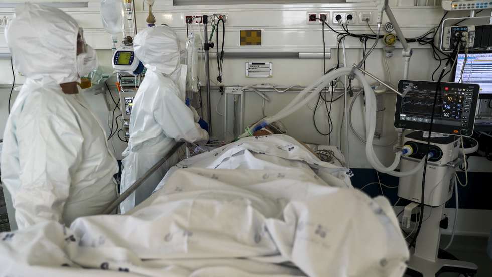 Dois elementos da equipa médica cuidam de uma paciente hospitalizado na Unidade de Cuidados Intensivos covid-19