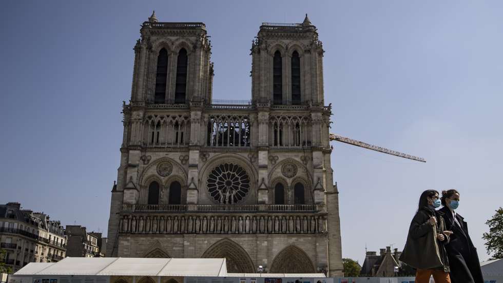 epa09115590 Pedestrians wearing protective face masks walk past Notre-Dame Cathedral on Easter Sunday in Paris, France, 04 April 2021. New enhanced lockdown measures have come into effect nationally over Easter weekend in France to help combat the third wave of Covid19 coronavirus. Schools and daycares have closed, non-essential shops are to close across France, the consumption of alcohol has been restricted in some key areas of cities to limit social gatherings, and a night time curfew between 7pm and 6am are enforced, along with travel restrictions - although the government has allowed a 'tolerance window' over Easter weekend for people to relocate ahead of the three-week strict lockdown. As a result, many Parisians have fled the capital for the countryside, or to resettle with family members to help care for their children as schools remain closed for the foreseeable future.  EPA/IAN LANGSDON