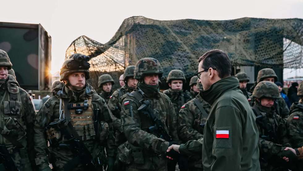 epa09572684 A handout photo made available by Chancellery of the Prime Minister shows Polish Prime Minister Mateusz Morawiecki (R), during a meeting with soldiers and officers of the services involved in securing the Polish border with Belarus in the region of Kuznica, eastern-Poland, 09 November 2021. On 08 November morning, the media published information about a large group of migrants planning to cross the Belarusian border with Poland. The Ministry of National Defense informed in the afternoon that the services of the Ministry of Interior and Administration and soldiers had managed to stop the first mass attempt to cross the border. Currently, migrants have set up a camp in the Kuznica region. EPA/ADAM GUZ / CHANCELLERY OF PRIME MINISTER HANDOUT HANDOUT EDITORIAL USE ONLY/NO SALES