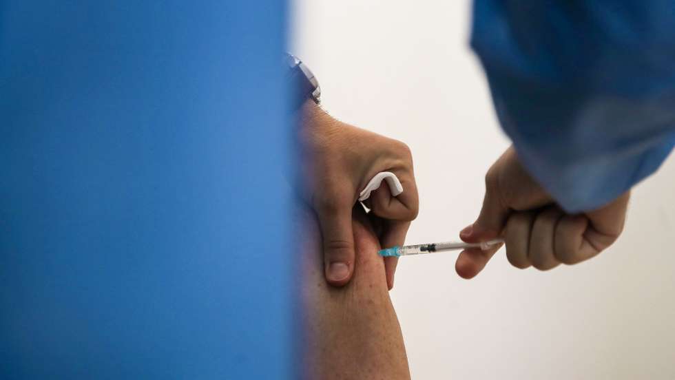 Um enfermeiro administra a 3ª dose da vacina contra a covid-19