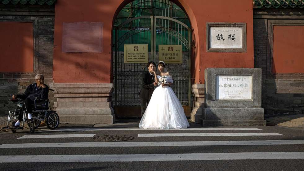 epa09510949 A couple pose for their pre-wedding photos next to a man sitting in a wheelchair, in the Hutong neighborhood, on the last day of the 'Golden Week' holiday, in Beijing, China, 07 October 2021. The 'National Day Golden Week' holiday begins on 01 October when most of the people in China have a 7-day national holiday.  EPA/ROMAN PILIPEY