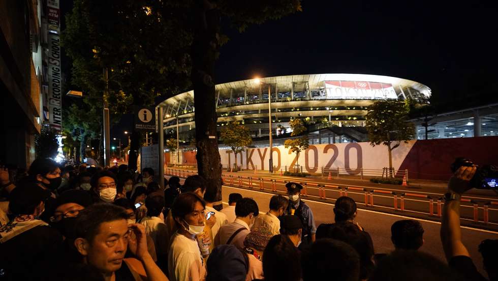 epa09406111 People gather before the  Olympic Stadium during the Closing Ceremony of the Tokyo 2020 Olympic Games at the Olympic Stadium in Tokyo, Japan, 08 August 2021.  EPA/FRANCK ROBICHON
