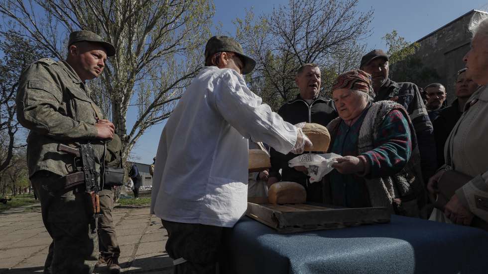 epa09917331 A picture taken during a visit to Luhansk organized by the Russian military shows servicemen of the self-proclaimed Donetsk People's Republic distribute bread to local people during distributing humanitarian aid in Mariupol, Ukraine, 29 April 2022. According to Eduard Basurin, spokesman of the self-proclaimed Donetsk People's Republic (DPR): 'after two months of continued hostility in the city, the main battles in Mariupol are over'. On 24 February Russian troops had entered Ukrainian territory in what the Russian president declared a 'special military operation', resulting in fighting and destruction in the country, a huge flow of refugees, and multiple sanctions against Russia.  EPA/SERGEI ILNITSKY