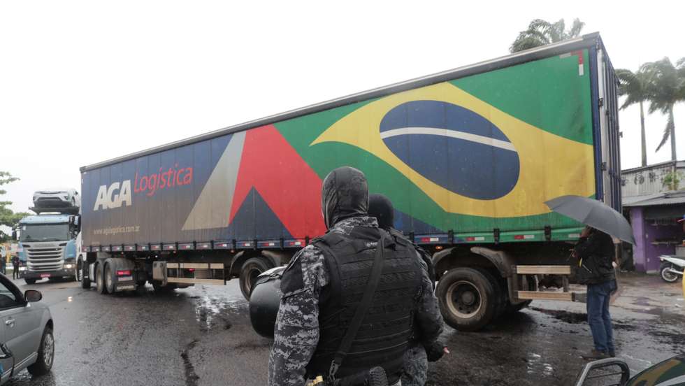 epa10279501 A police officer stands guard as truckers block roads in Rio de Janeiro, Brazil, 01 November 2022. According to videos released on social networks by leaders of that rebellion, they will only end the protest when ' the Army intervenes' to 'prevent the return of communism'. Bolsonaro, who lost the elections by a difference of 1.8 points against Lula, had not yet ruled on the result and had not been seen in public since he voted in Rio of Janiero.  EPA/ANDRE COELHO