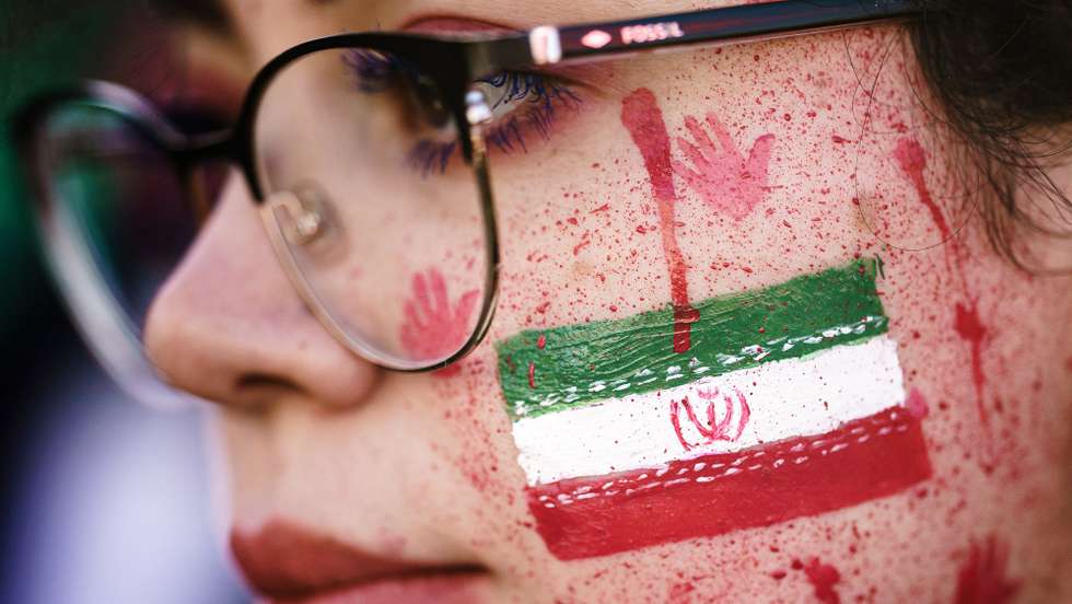 epa10364983 epa10229335 A protester shows red paint in her face, resembling blood splatters and bloody handprints next to the national Iranian emblem, during a rally in solidarity with Iranian protests following the death of Mahsa Amini, in Berlin, Germany, 07 October 2022. Amini, a 22-year-old Iranian woman, was arrested in Tehran on 13 September by the police unit responsible for enforcing Iran's strict dress code for women. She fell into a coma while in police custody and was declared dead on 16 September.  EPA/CLEMENS BILAN  EPA-EFE/CLEMENS BILAN