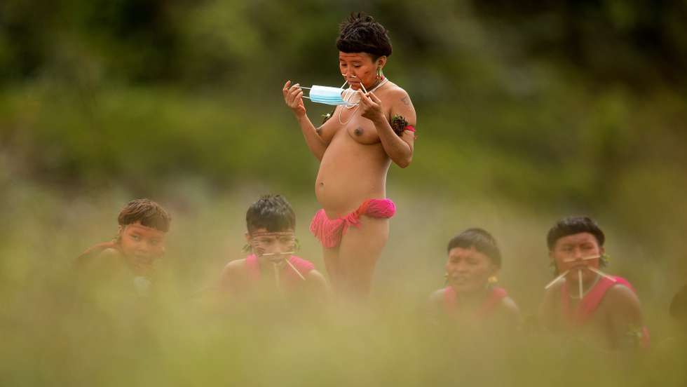 epa08758530 YEARENDER 2020 
COVID-19 PANDEMIC

A member of the Yanomami people prepares to put on a face mask in the Surucucu region, Alto Alegre municipality, Roraima state, Brazil, 01 July 2020. The coronavirus has entered the largest indigenous land in Brazil and has already killed at least four members of the Yanomami people, including three babies. In the states of Roraima, bordering Venezuela, and Amazonas (north), the Yanomami villages are located deep in the Amazon jungle, in an area of nine million hectares - a surface similar to that of Austria - with just 28,000 inhabitants.  EPA/JOEDSON ALVES *** Local Caption *** 56189455