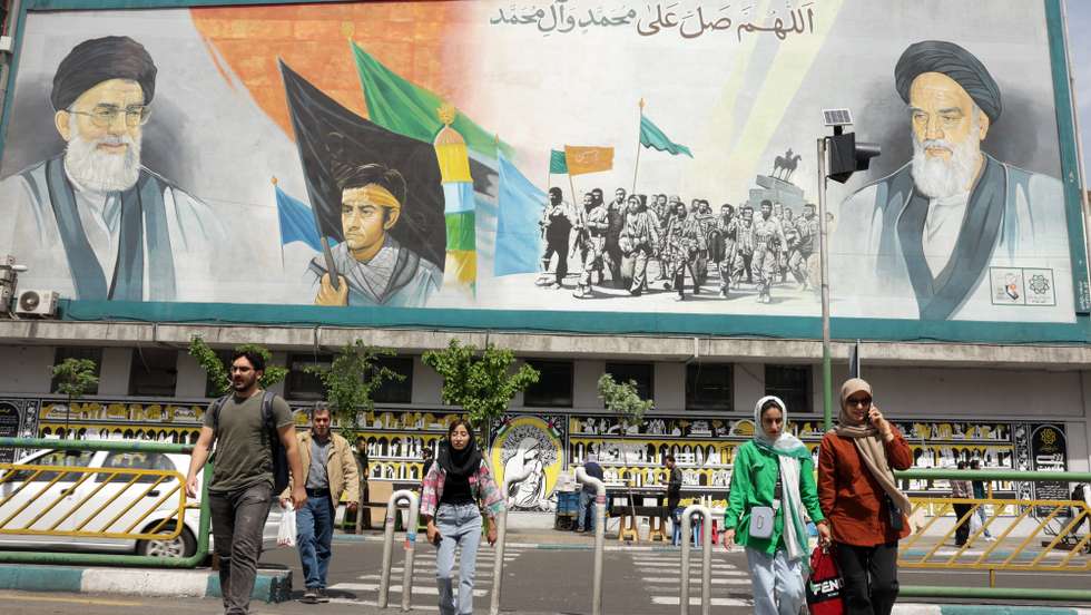 epa12017452 Iranians walk next to huge wall painting of Iranian supreme leader Ayatollah Ali Khamenei (Top-R) and late supreme leader Ayatollah Ruhollah Khomeini (Top-L) in a street, in Tehran, Iran, 08 April 2025. Iranian Foreign Minister Abbas Araqchi said on 08 April that top Iranian and US officials will hold indirect negotiations in Oman on 12 April.  EPA/ABEDIN TAHERKENAREH