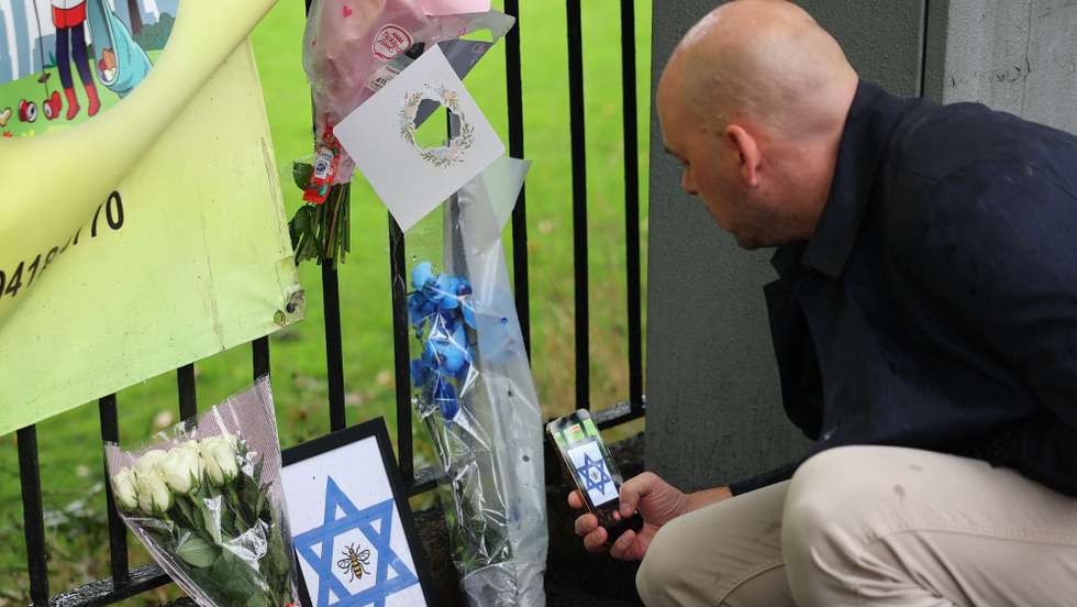 epa12427117 A person photographs flowers and tributes left at the scene of a deadly terror attack  in Manchester, Britain, 03 October 2025. Two people died after a car and stabbing attack at a synagogue in Manchester on 02 October, and the attacker, who has been named as 35-year-old British citizen Jihad Al-Shamie, was shot dead by police.  EPA/ADAM VAUGHAN
