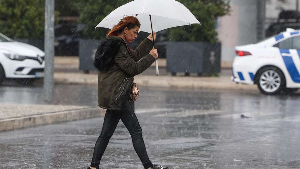 Uma traseunte passa com chapéu de chuva na zona de Algés em Oeiras num dia de temporal, 14 de dezembro de 2022. TIAGO PETINGA/LUSA