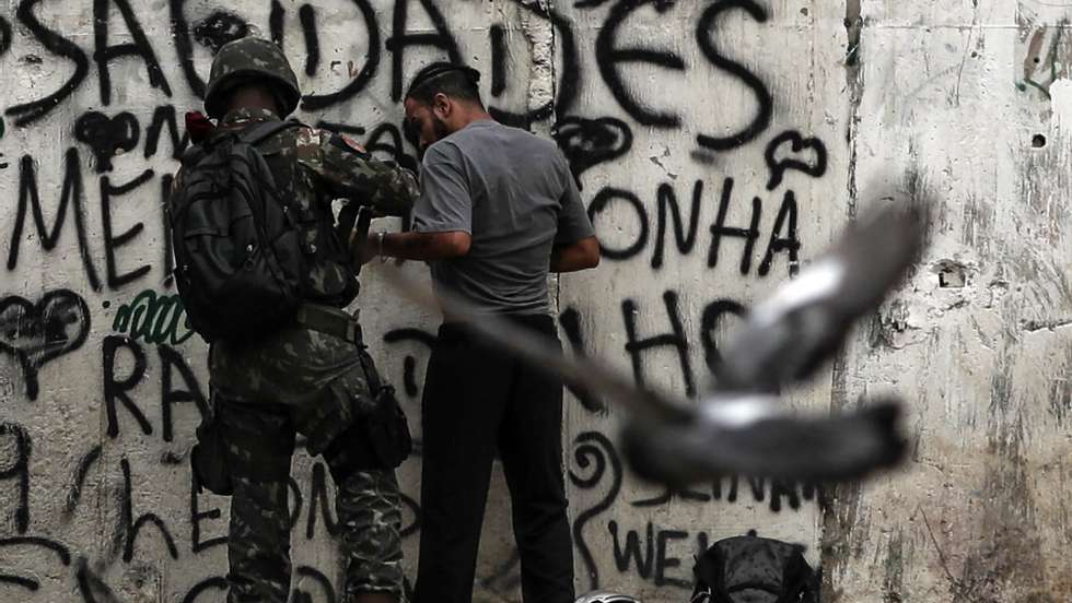 epa07035265 aA local man is searched as armed military soldiers patrol in a neighbohood in Rio de Janeiro, Brazil, 20 September 2018. Nearly 450 members of the Armed Forces participate in an operation against drug trafficking at the Jacarezinho slum in Rio de Janeiro.  EPA/ANTONIO LACERDA