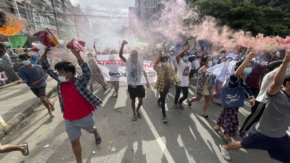 epa09319894 Demonstrators holding posters and flares as they march during an anti-military coup protest at downtown area in Yangon, Myanmar, 03 July 2021. According to the UN Office for the Coordination of Humanitarian Affairs (UN OCHA), at least 230,000 people have been displaced due to violence, armed clashes and insecurity since the military seized power on 01 February 2021.  EPA/STRINGER
