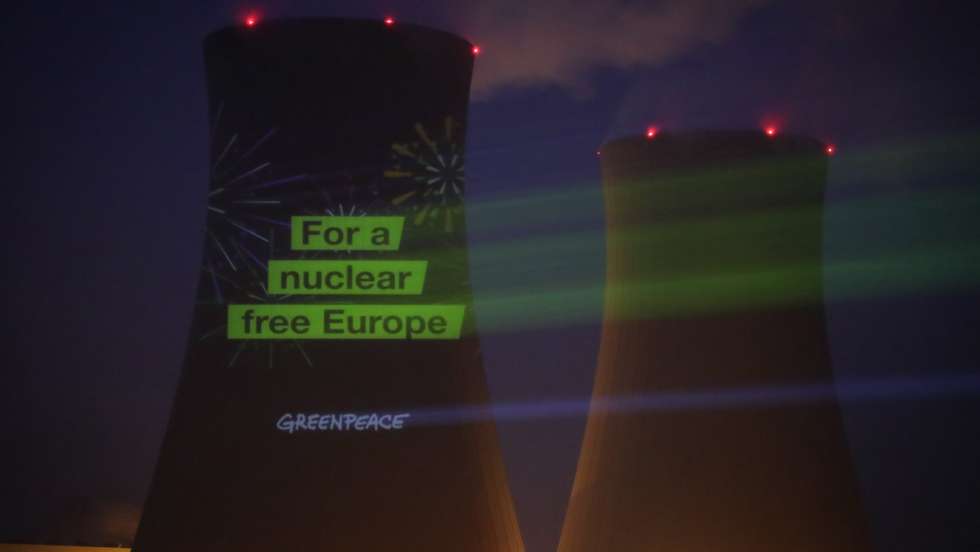 epa09660693 Greenpeace activists project the slogan 'For a nuclear free Europe' onto one of the cooling towers of the Grohnde Nuclear Power Plant (Kerncentrale Grohnde - KGW) in Emmerthal, northern Germany, 30 December 2021. The power plant, mainly owned by PreussenElektra, is one of three German nuclear power plants that will be decommissioned on 31 December 2021.  EPA/FOCKE STRANGMANN
