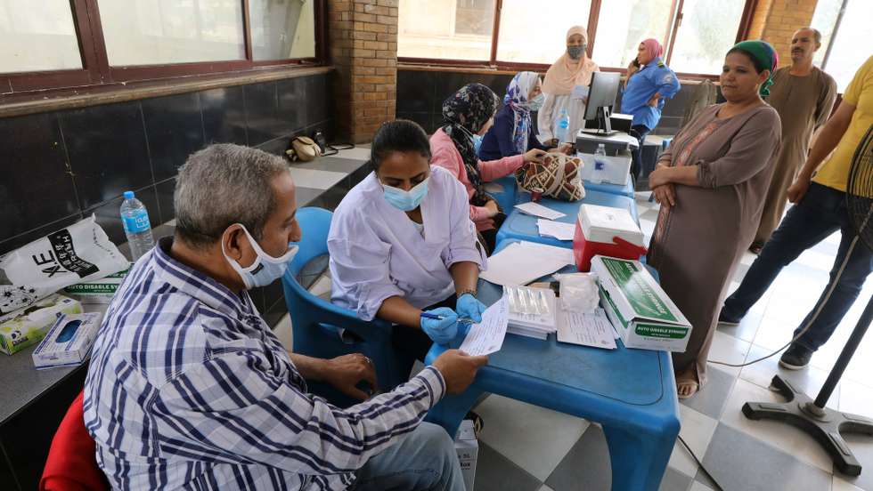 epa09489399 A man (L) prepares to receive a dose of COVID-19 vaccine at the Rawd Al-Faraj youth center in Cairo, Egypt, 26 September 2021.  EPA/KHALED ELFIQI