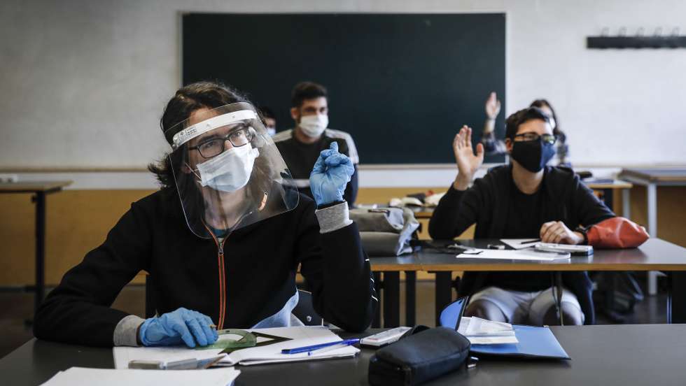 Uma aluna usa uma viseira, máscara de proteção respiratória e luvas contra a covid-19 durante uma aula, no primeiro dia após o alívio das medidas de emergência devido à situação epidemiológica da covid-19, em Sintra, 18 de maio de 2020. O Governo aprovou no dia 15, novas medidas que entram hoje em vigor, entre as quais a retoma das visitas aos utentes dos lares de idosos, a reabertura das creches, aulas presenciais para os 11.º e 12.º anos e a reabertura de algumas lojas de rua, cafés, restaurantes, museus, monumentos e palácios. RODRIGO ANTUNES/LUSA