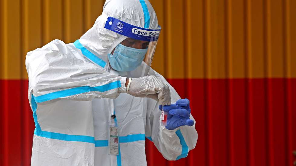 epa09625705 A health worker collects swab samples to detect Covid-19 at a bus stand in Bangalore, India, 06 December 2021. India reported at least 21 confirmed cases of coronavirus Omicron variant in Delhi, Rajasthan, Maharashtra, Gujarat and Karnataka.  EPA/JAGADEESH NV