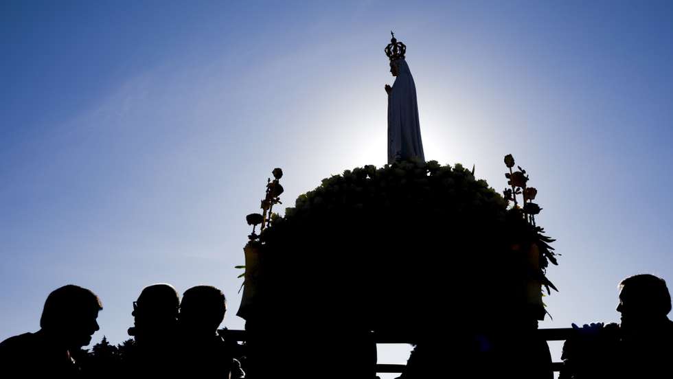 epa10240381 The statue of Our Lady of Fatima is silhouetted against a bright blue sky as it is carried on a litter during the second day of the annual international pilgrimage to the Shrine of Fatima, Portugal, 13 October 2022. This year's Fatima Pilgrimage takes place on on 12 and 13 October 2022.  EPA/PAULO CUNHA