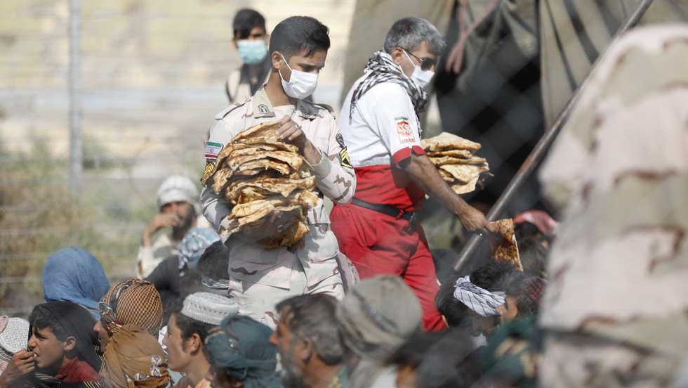 epa09420825 A handout photo made available by Iranian Red Crescent shows an Iranian soldier distributes foods among Afghan Afghan refugee gather in Iran-Afghanistan border in Sistan-Blochestan province, south-eastern Iran, 16 August 2021 (issued 19 August 2021). According to Iranian Red Crescent official website, after Taliban took-over the rule in Afghanistan, some Afghan refugees fled to the Iranian borders hoping to enter to Iran. Reports state refugees were sent back to Afghanistan the next day after getting food and help.  EPA/MOHAMMAD JAVADZADEH HANDOUT  HANDOUT EDITORIAL USE ONLY/NO SALES