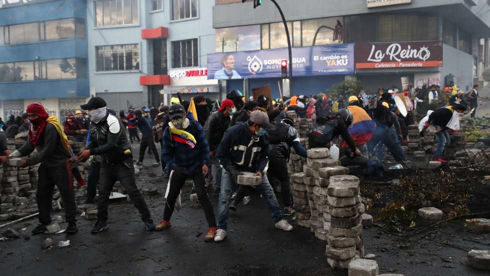 epa10030940 Demonstrators set up barricades to protect themselves during clashes with members of the police around the House of Culture in Quito, Ecuador, 23 June 2022. The center of Quito once again became the scene of intense clashes between the Ecuadorian Police and the demonstrators who, for the eleventh consecutive day, participated in the protests against the high cost of living and the economic policies of the Government of President Guillermo Lasso.  EPA/Jose Jacome