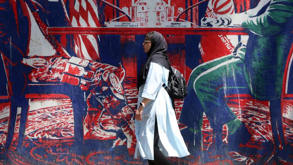 epa13055977 An Iranian woman walks past an anti-US mural (depicting an Iranian and US negotiation table) next to the former US embassy in Tehran, Iran, 22 June 2026. Leaders of the Iranian negotiation team, Mohammad Bagher Ghalibaf and Abbas Araghchi, left the Lucerne Summit in Switzerland after 18 hours of talks with the US, Pakistan, and Qatar.  EPA/ABEDIN TAHERKENAREH RESTRICTIONS: NO Access Israel Media/Persian Language TV Stations Outside Iran/Strictly No Access BBC Persian/VOA Persian/Manoto TV/Iran International TV. (As mandated by Iran's Directorate General for Foreign Media) --