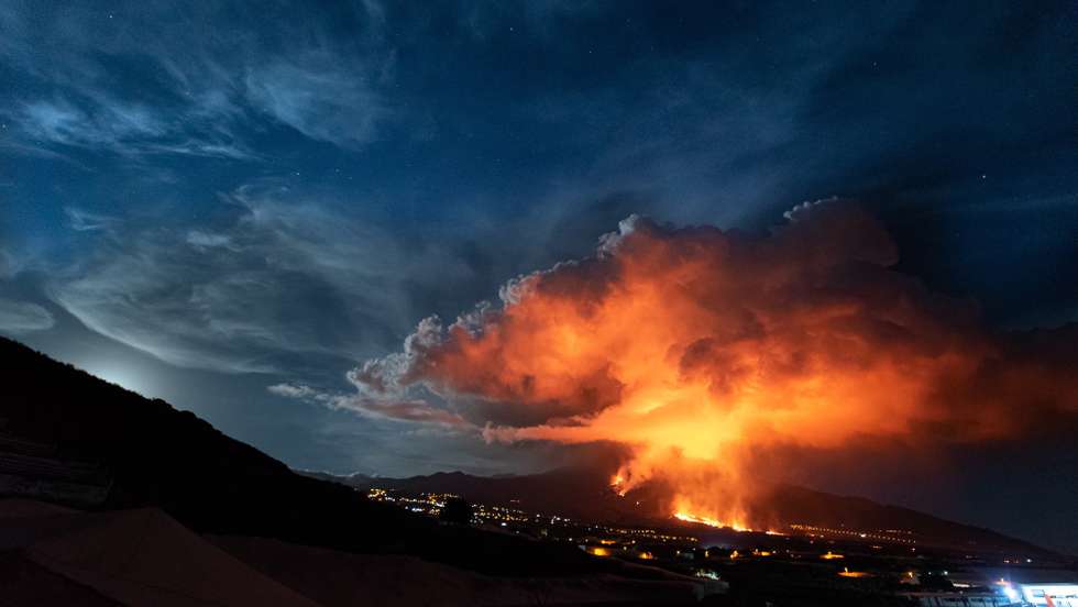epa09592807 Lava and smoke rise from the Cumbre Vieja volcano as it is seen from Los Llanos de Aridane, La Palma, Canary Islands, Spain, 19 November 2021. The Cumbre Vieja volcano erupted on 19 September and has spewn out smoke, ash and lava since then.  EPA/Miguel Calero